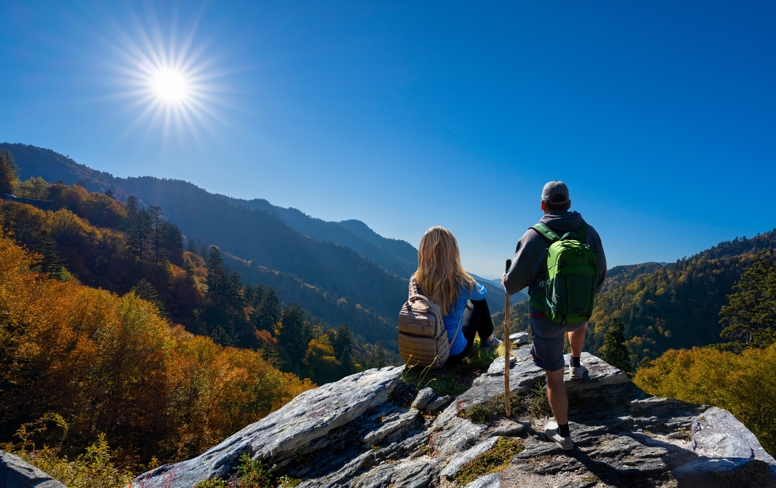 man and woman with hiking gear looking out at mountain view 