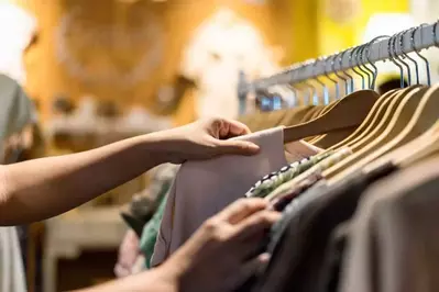 someone browses shirts on a rack