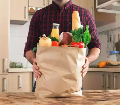 man with paper grocery bag full of food