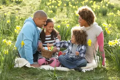 Happy family with an Easter basket sitting in the grass near their cabin rental in the mountains of North Carolina