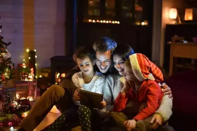 Family huddled together on a chair watching something on a tablet