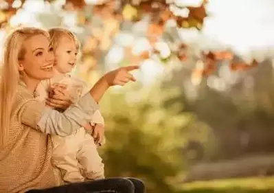 mother holding daughter outside pointing away 