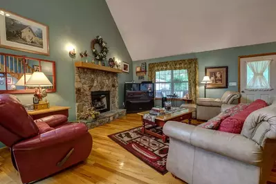 open living room with a vaulted ceiling and rock fireplace