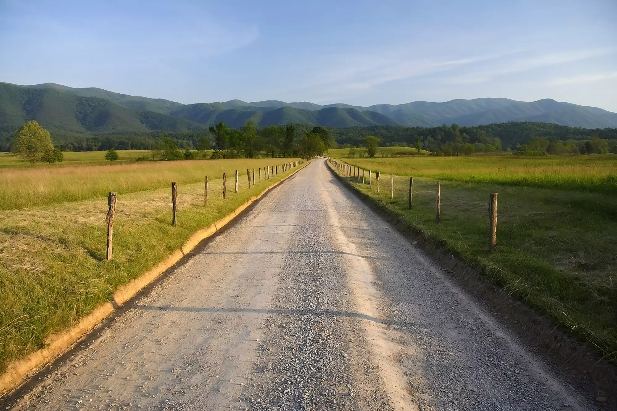 gravel road through meadow surrounded by mountains